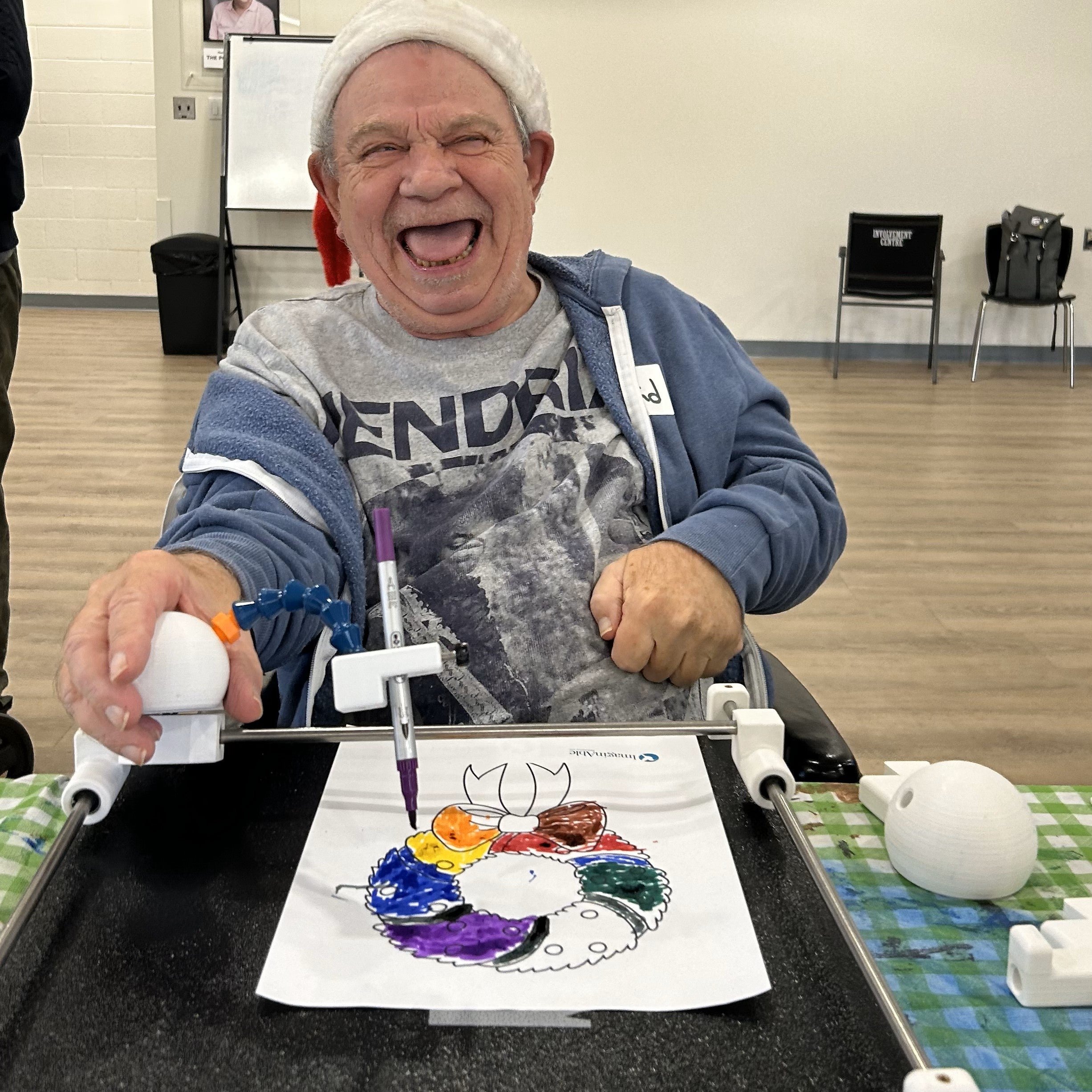 Man with Cerebral Palsy smiling while colouring with Guided Hands.