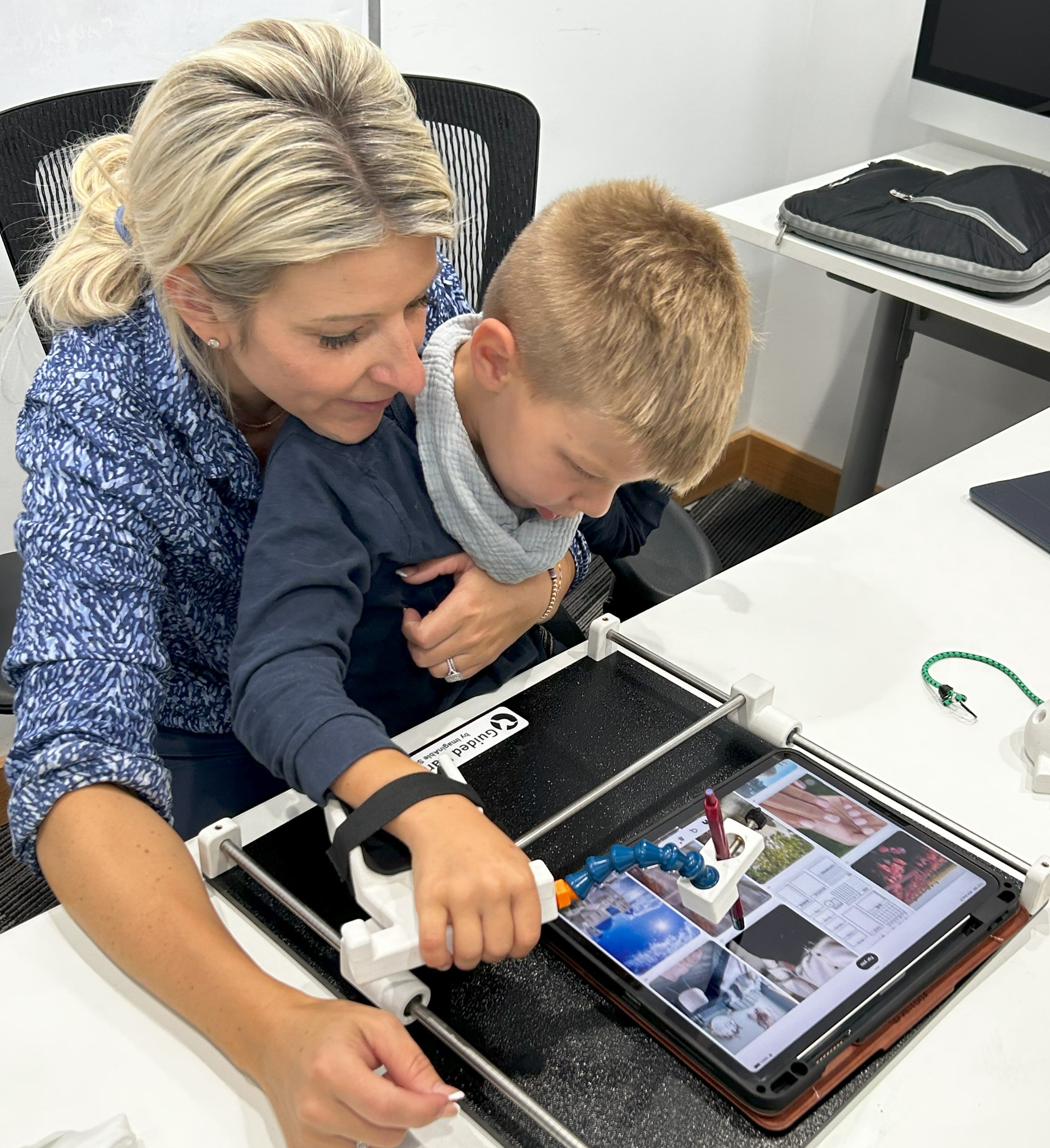 Mother and Son looking at iPad that the son is using with Guided Hands