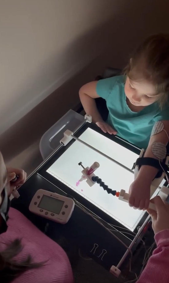 Little girl using Guided Hands to colour with a light board under the paper